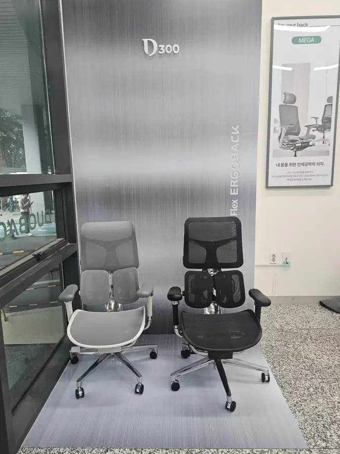 Two SIHOO D300 ergonomic chairs (gray and black) displayed in a retail setting, with "D300" and "Flex ERGOBACK" branding in the background.